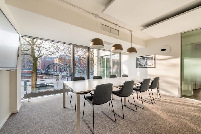 Moderner Besprechungsraum mit Tisch, Stühlen, Bildschirm und großer Glasfront